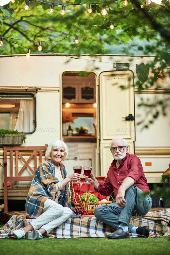Happy elderly couple sitting on the porch of their camper van - Stock Photo - Images