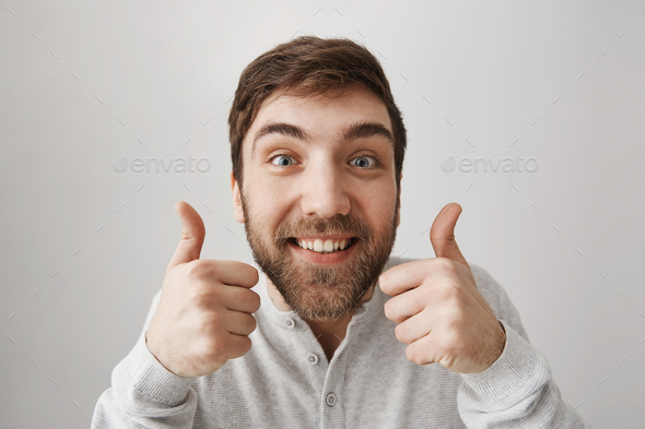 Approval and positive reaction concept. Studio shot of funny european guy smiling broadly, showing