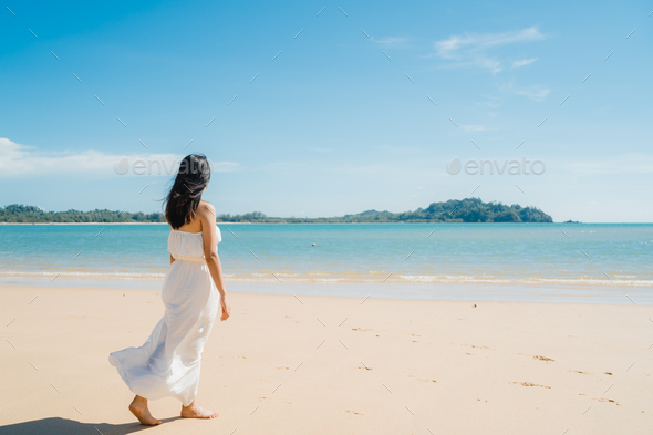 Beautiful young Asian woman happy relax walking on beach near sea. - Stock Photo - Images