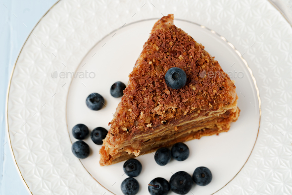 Piece of honey cake with nuts on white plate