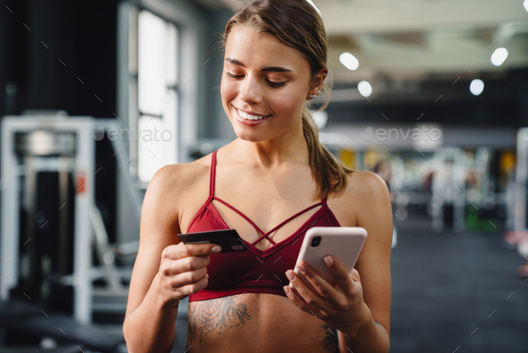 Woman fitness coach using mobile phone in gym