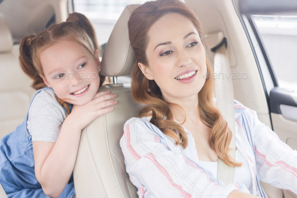 portrait of smiling mother driving car with daughter on passengers seat