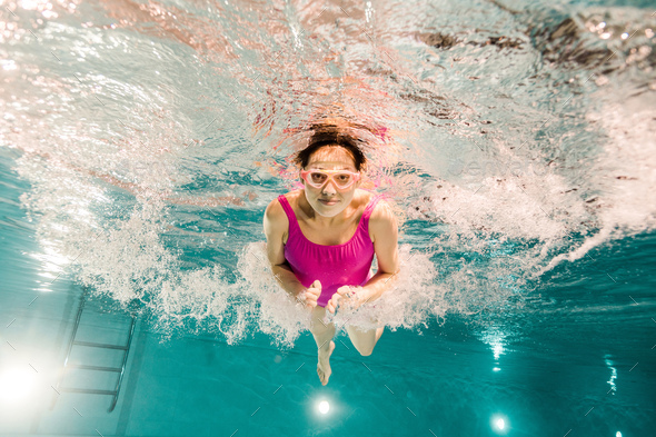 woman diving in googles underwater in swimming pool - Stock Photo - Images