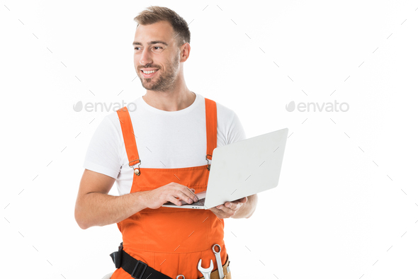 portrait of handsome auto mechanic in orange uniform holding laptop isolated on white
