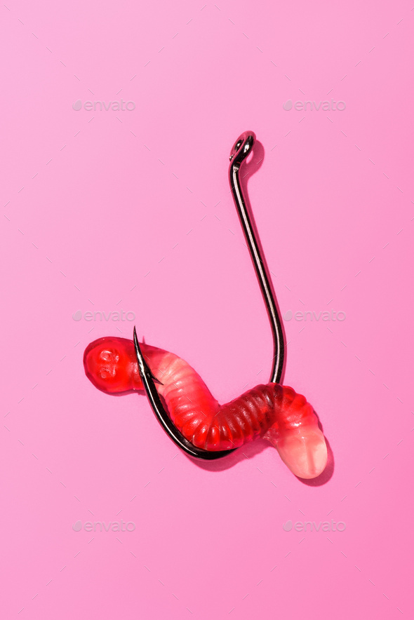 red gummy worm on fishing hook on pink