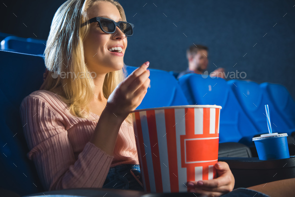 smiling woman in 3d glasses with popcorn watching film alone in cinema