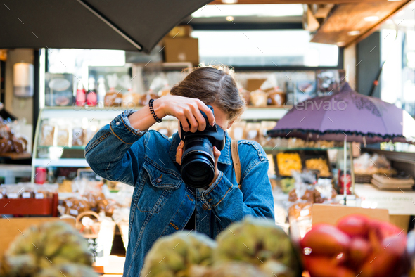 woman with obscured face by camera taking picture in shop