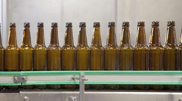 Beer bottling plant with moving belts, rows of bottles, automated process, capping and labelling