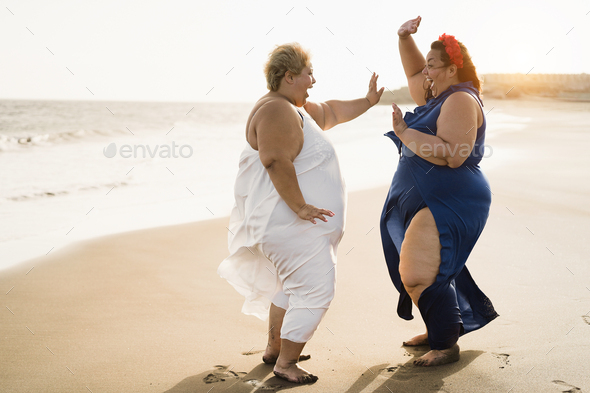 Curvy Women Friends Dancing On The Beach Having Fun During Summer Travel Vacation Focus On