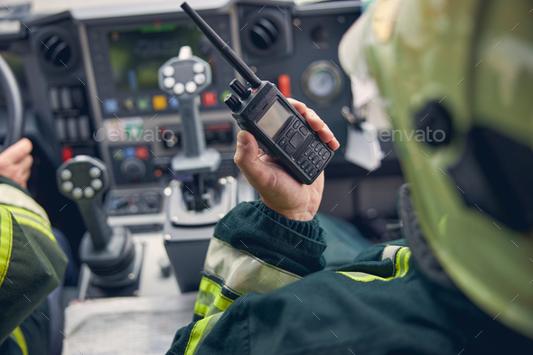 Firefighter holding walkie talkie at fire machine Stock Photo by Iakobchuk