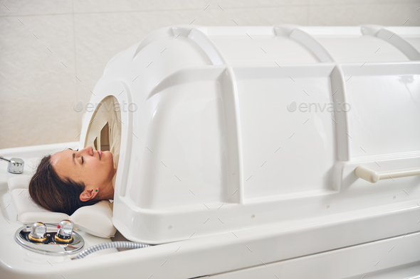 Pleased lady in spa capsule relaxing with closed eyes