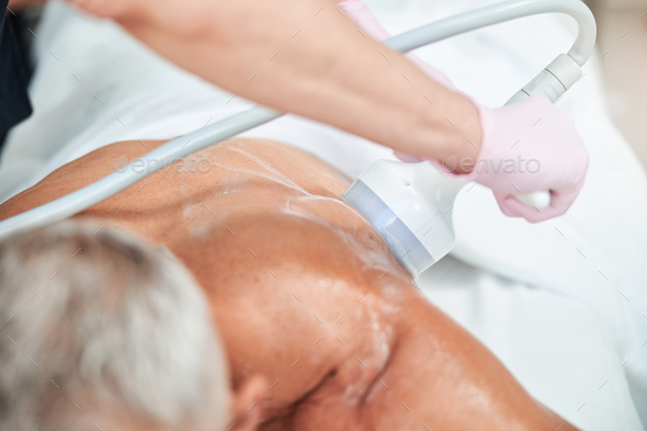 Professional spa staff conducting skin-revival procedure for an elderly man