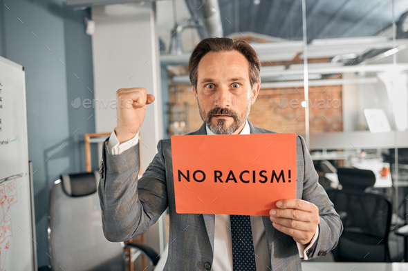 Businessman holding a poster with the word no racism