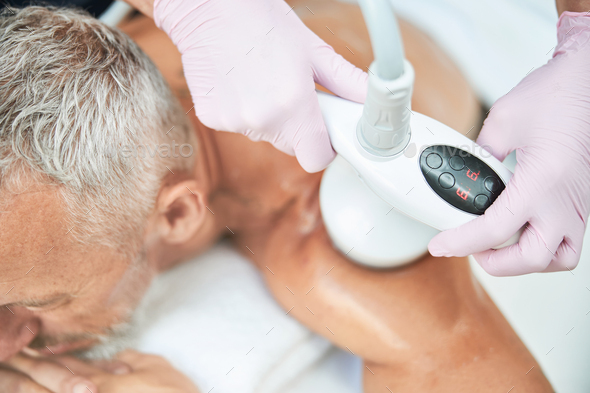Eldelry man undergoing a process of ultrasonic cavitation - Stock Photo - Images