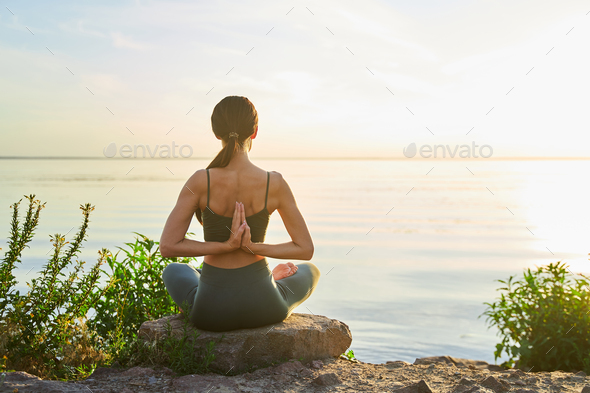 Sporty young woman doing reverse prayer pose outdoors by the sea
