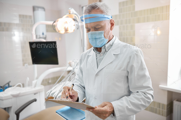 Attentive dental expert holding a clipboard at work