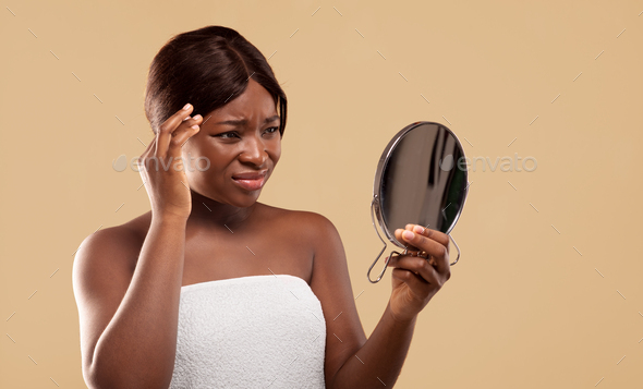 Sad Black Woman Looking To Mirror And Touching Face Suffering Skin Problems