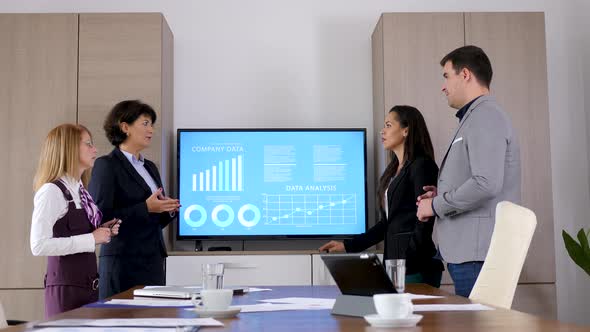 Business Team in Conference Room Beside a Big Screen TV alt