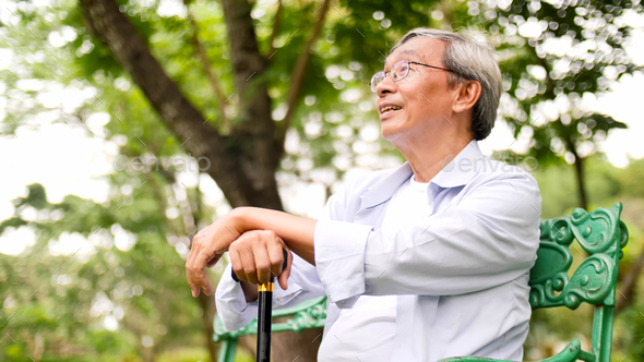 Happy asian man sitting on a bench at the park. - Stock Photo - Images