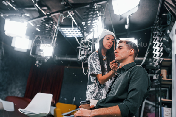Young man is preparing for TV online broadcast. Woman helps with make up - Stock Photo - Images