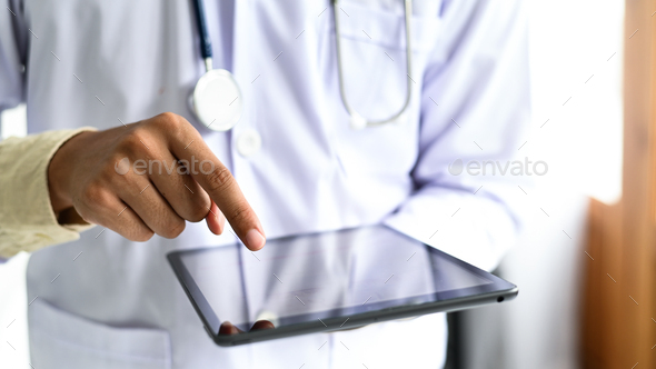 The man in a gown wearing tablet in his hand, Digital tablet search for medical information.
