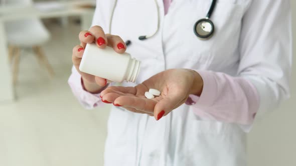 Female Doctor in White Coat Takes Pills Out of a Jar alt