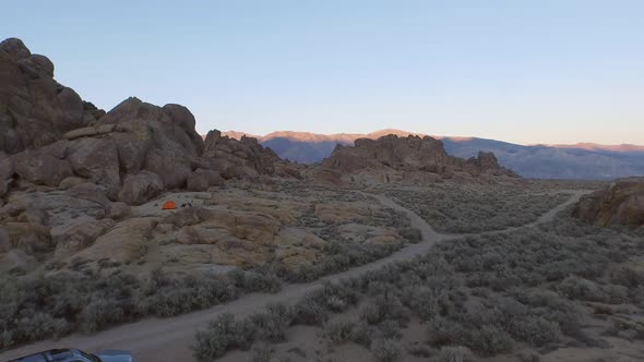 Aerial shot of a young man backpacker camping with his dog in a mountainous desert. alt