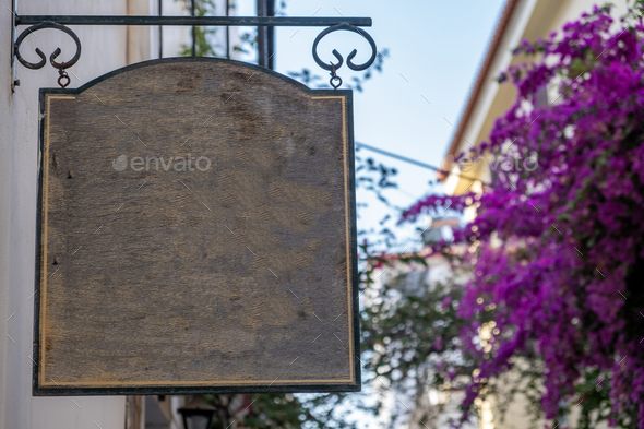 Blank empty wood sign hanging, blue sky and blooming bougainvillea,