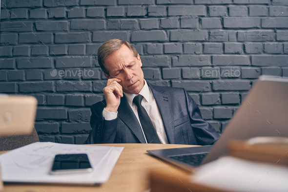 Bored senior businessman sleeping during online meeting