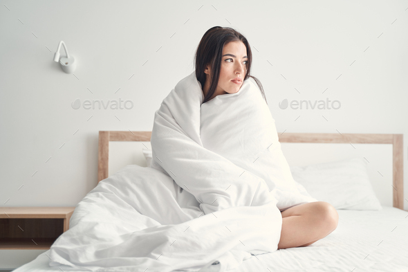 Low-spirited dark-haired Caucasian lady sitting in bed