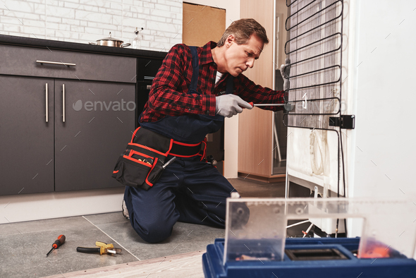 New refrigerator installation. Senior male technician checking refrigerator
