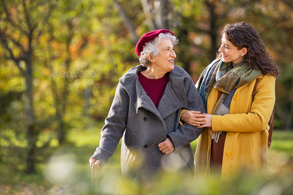 Senior woman walking with granddaughter in park during autumn - Stock Photo - Images