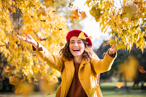 Young playful woman playing with leaves in autumn - Stock Photo - Images