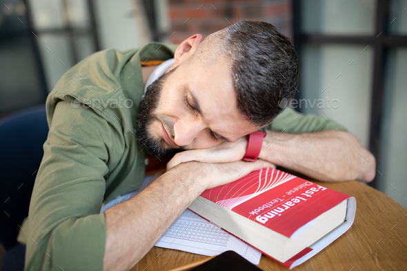 Dark-haired student sleeping after studying for too long