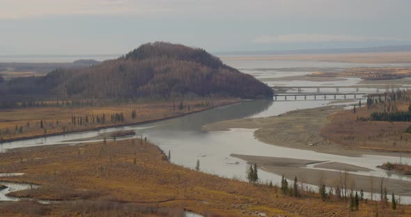 Helicopter aerial shot of snowy mountain as biplane comes int frame, drone alt