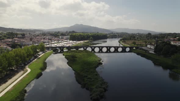 Aerial backward ascending over river with medieval bridge in background. Ponte de Lima in Portugal