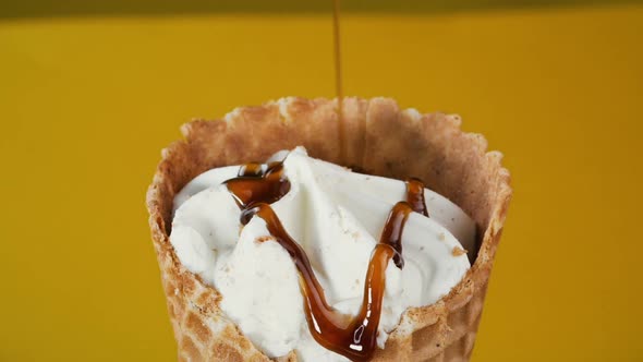 Vanilla Ice Cream Cone Is Poured with Caramel. Ice Cream with Topping, Close-up.