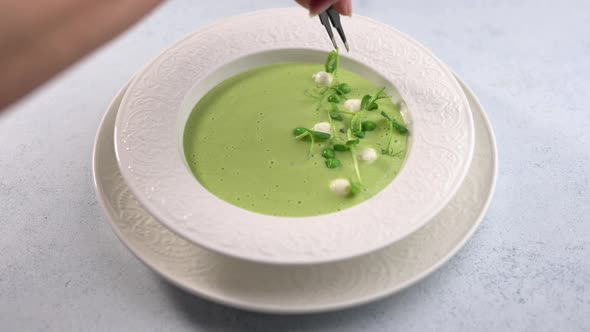 Woman's Hand Adorns Sprigs of Greenery Homemade Soup Puree of Green Peas