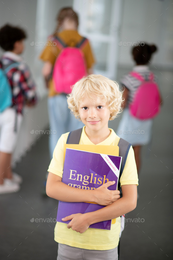 Blonde-haired schoolboy holding English grammar book