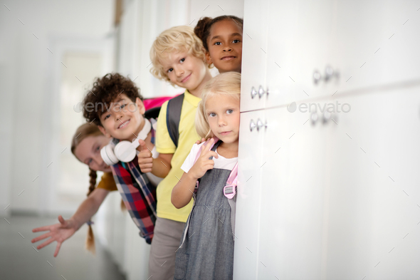 Cheerful children standing near lockers while enjoying school break
