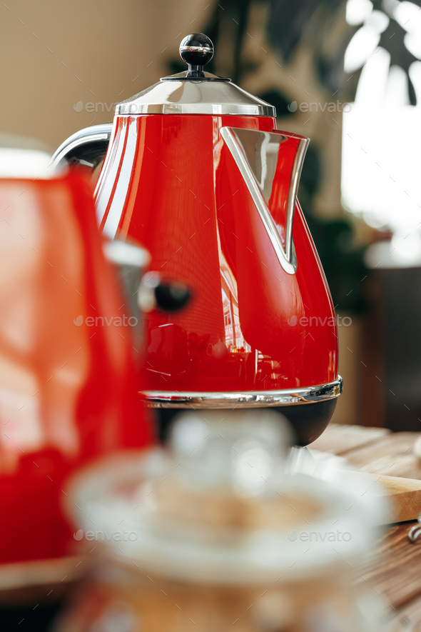 Red kettle on kitchen table close up