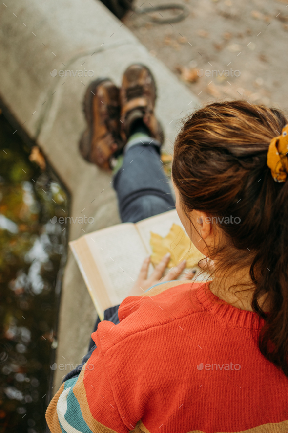 Young plus size woman reading book in fall autumn park in sun lights. Body positive, diversity, Body