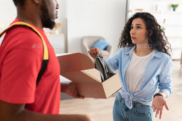 Confused frustrated lady unpacking box, holding clothes and complaining