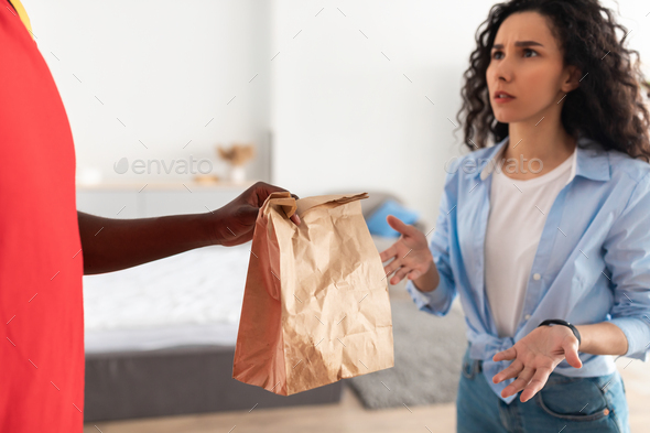 Closeup of confused woman complaining about bad food delivery