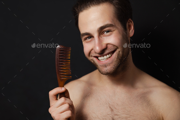 Smiling mid aged brunette shirtless man showing comb