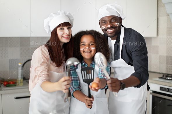 Family in hats and aprons, handsome African father, pretty Caucasian mother and cute teen mixed race