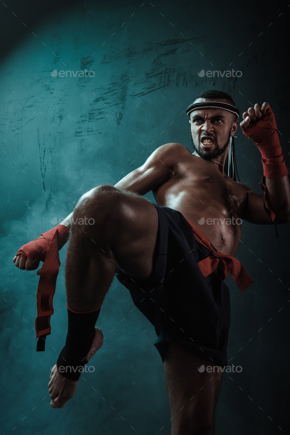 Low angle view of determined Muay thai fighter training thai boxing, ultimate fight concept
