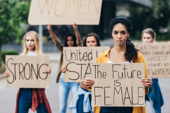 serious african american feminist holding placard with inscription the future is female near women