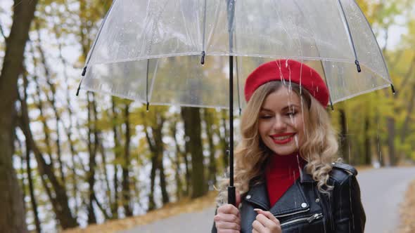 Smiling Happy Cheerful Woman in a Red Suit and a Biker Jacket with a Transparent Umbrella on a Rainy alt