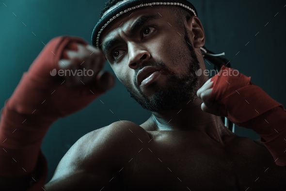 Close-up portrait of aggressive young Muay thai boxer training thai boxing, ultimate fight concept